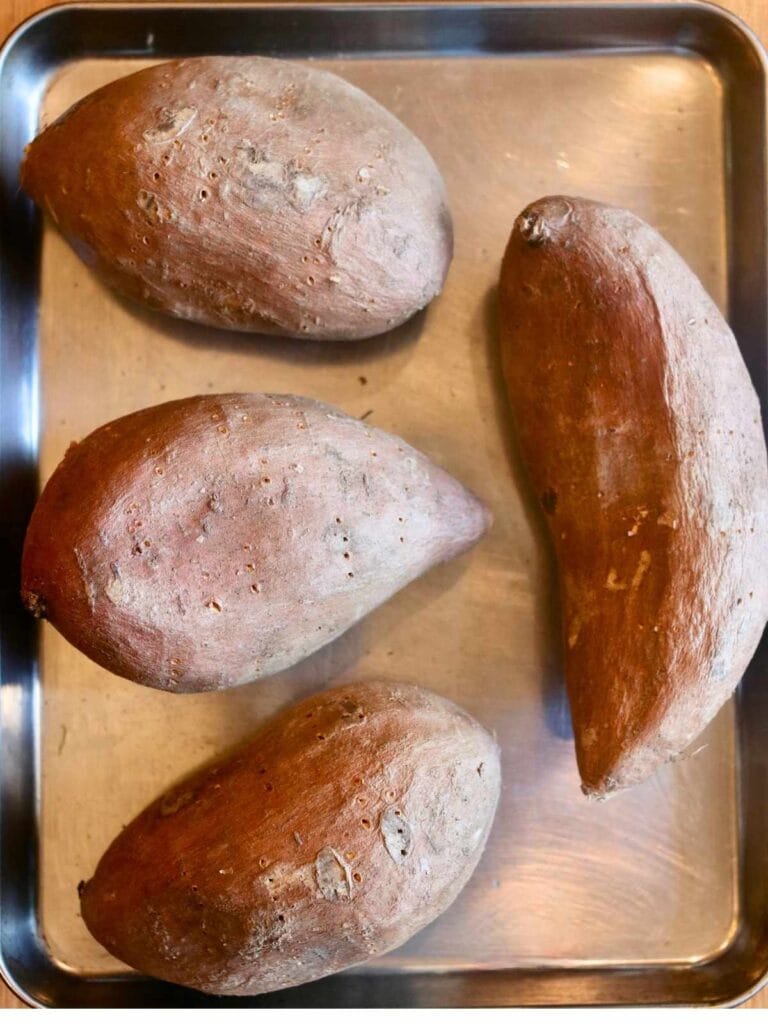 4 sweet potatoes on a baking sheet.