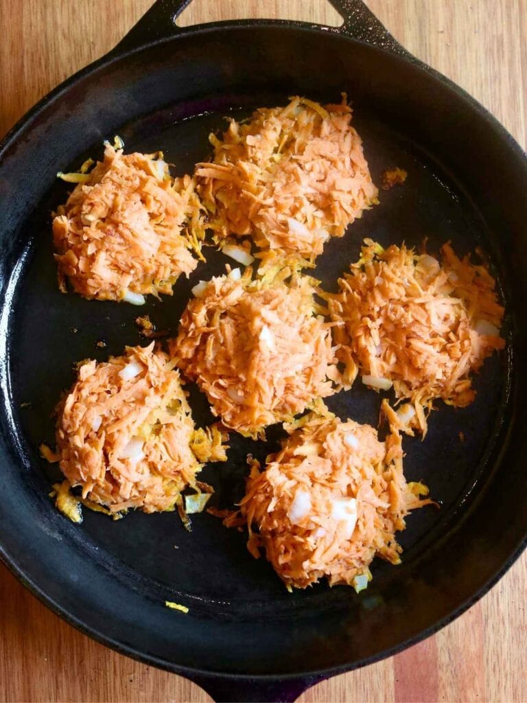 Sweet potato fritter patties cooking in hot cast iron skillet.