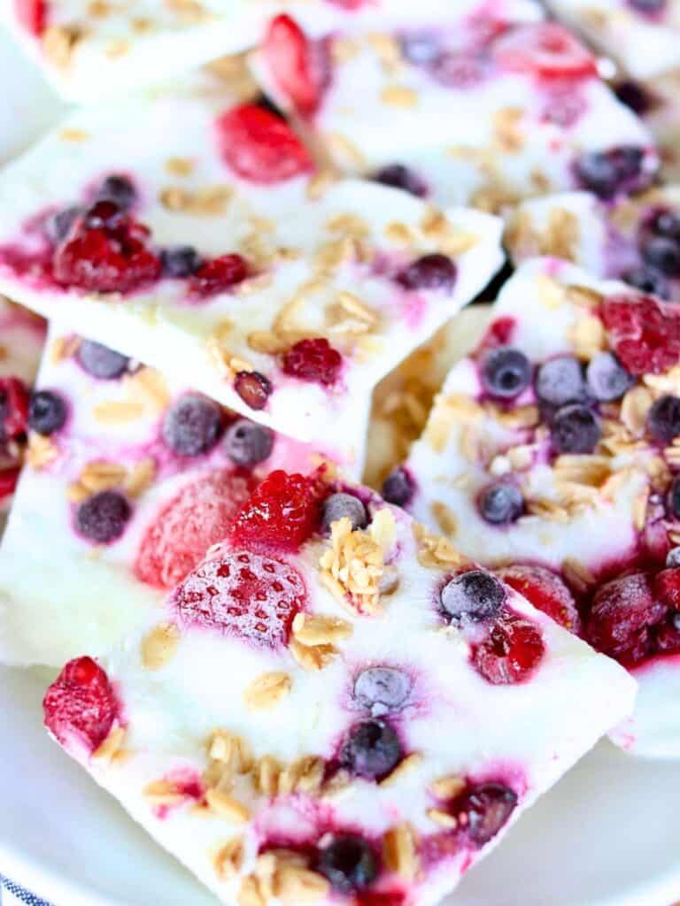Frozen yogurt bark with mixed berries and granola. The squares feature vibrant reds and purples of berries, creating a fresh, appetizing look.