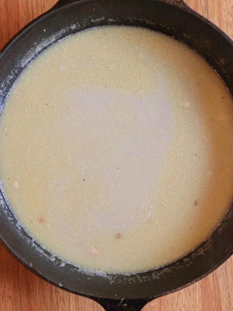 Adding cream and bone broth to a skillet to make a gravy.