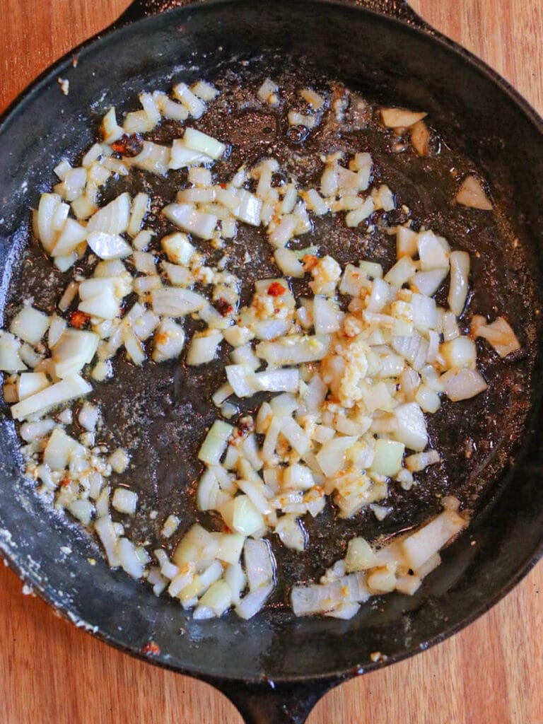 Chopped onion and minced garlic cooking in butter in a skillet.