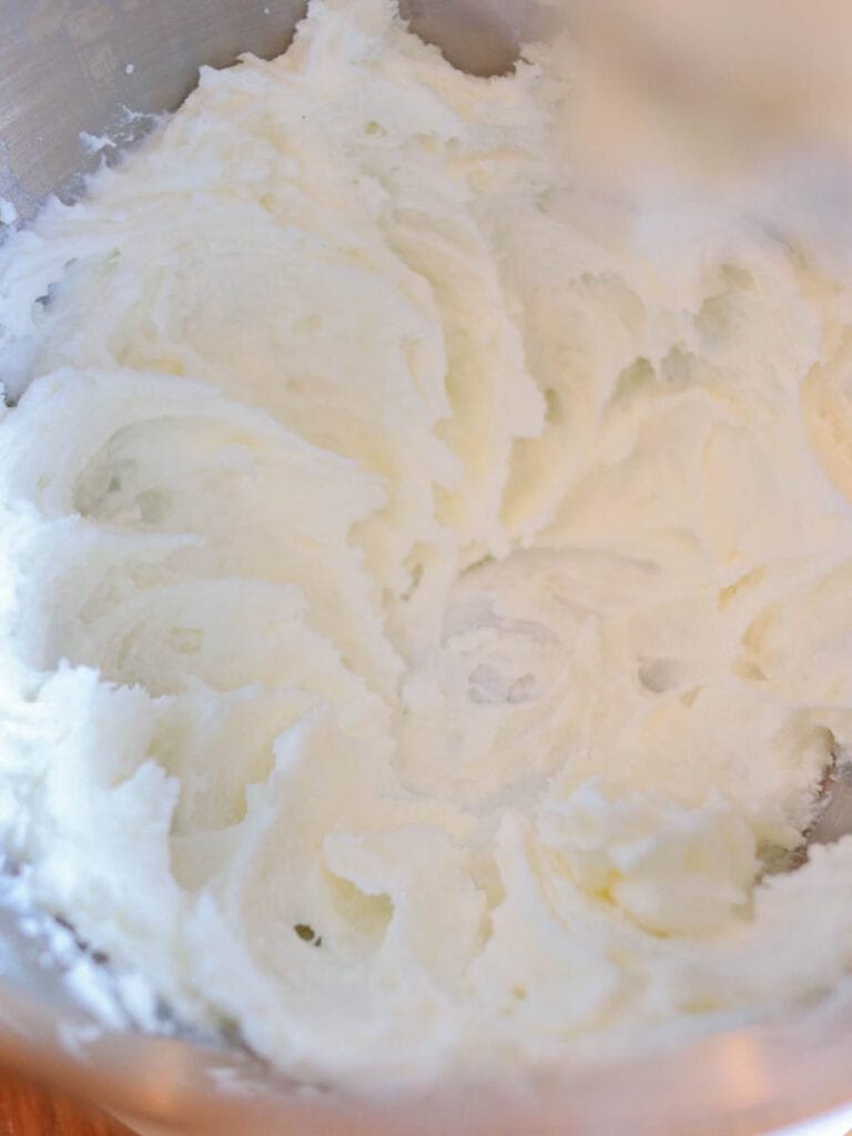 White whipped body butter in a stainless steel bowl.