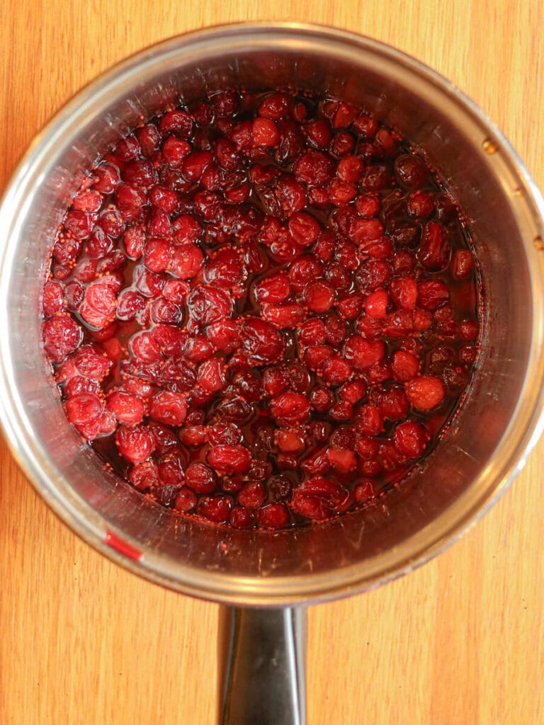 Cranberry compote cooking in a saucepan.