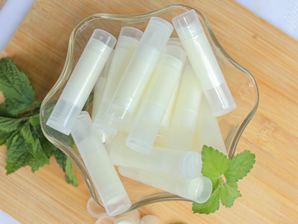 Homemade lip balm in a glass bowl on a wooden surface.