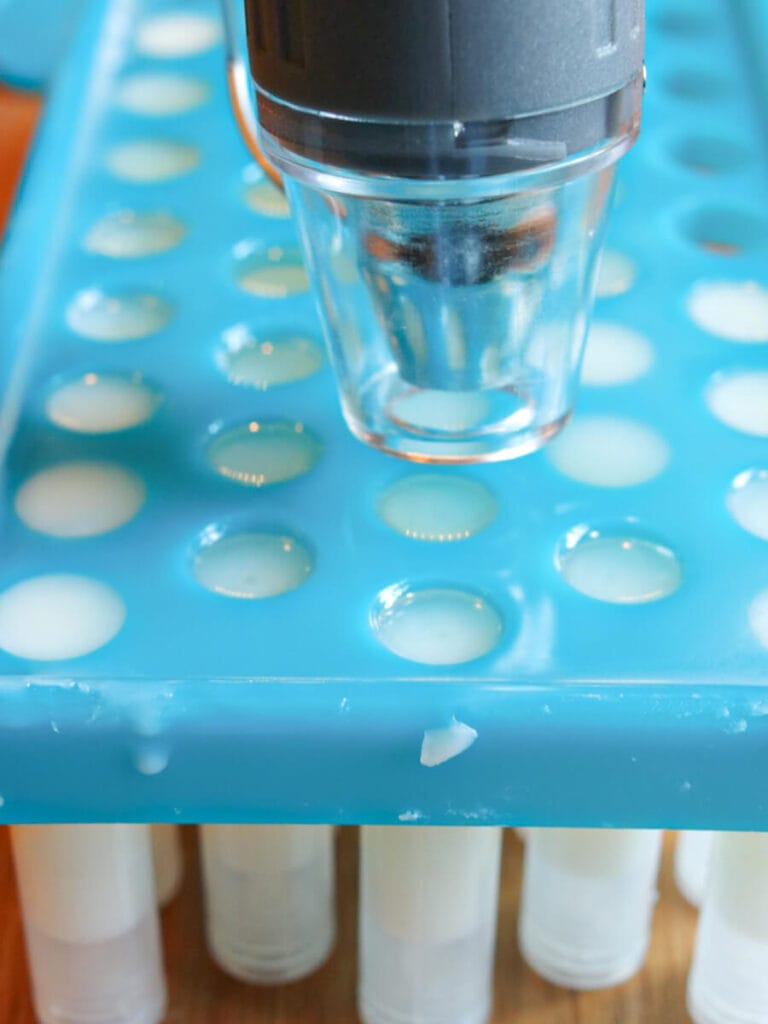 Using a heat gun to smooth the tops of lip balm.