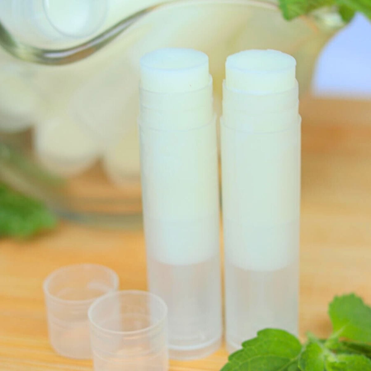 Closeup of two open tubes of lip balm on a wooden surface.