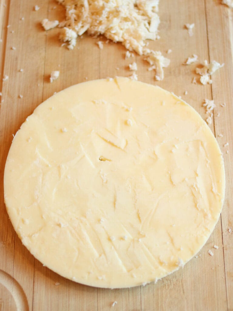 Round block of tallow after impurities have been removed on a wooden surface.
