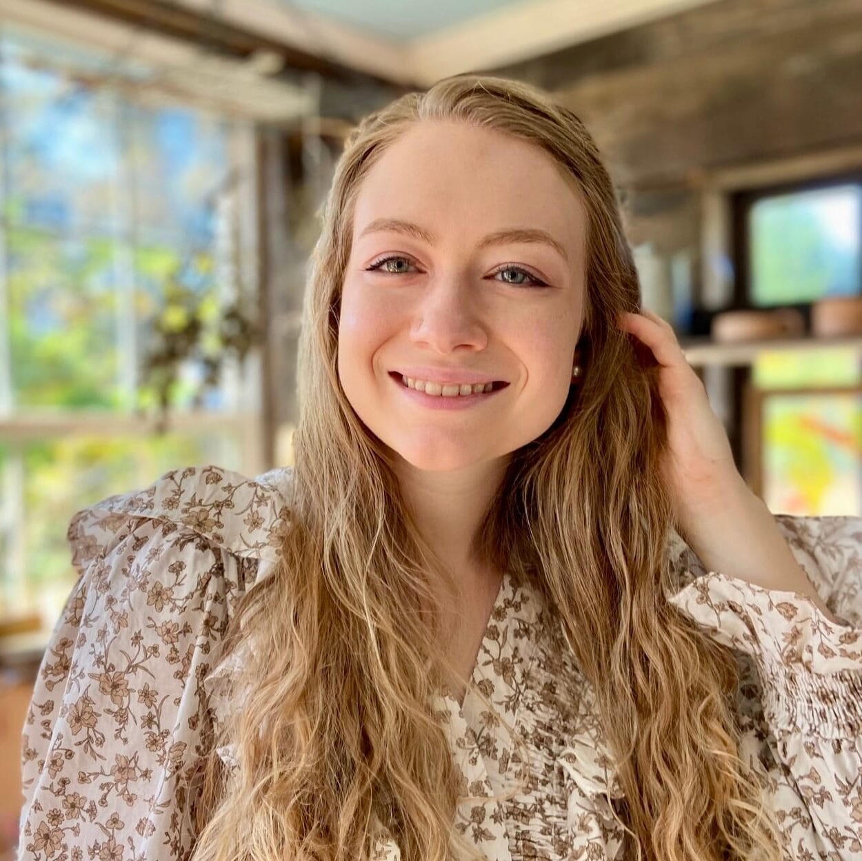 Woman smiling while standing in a sunny room.