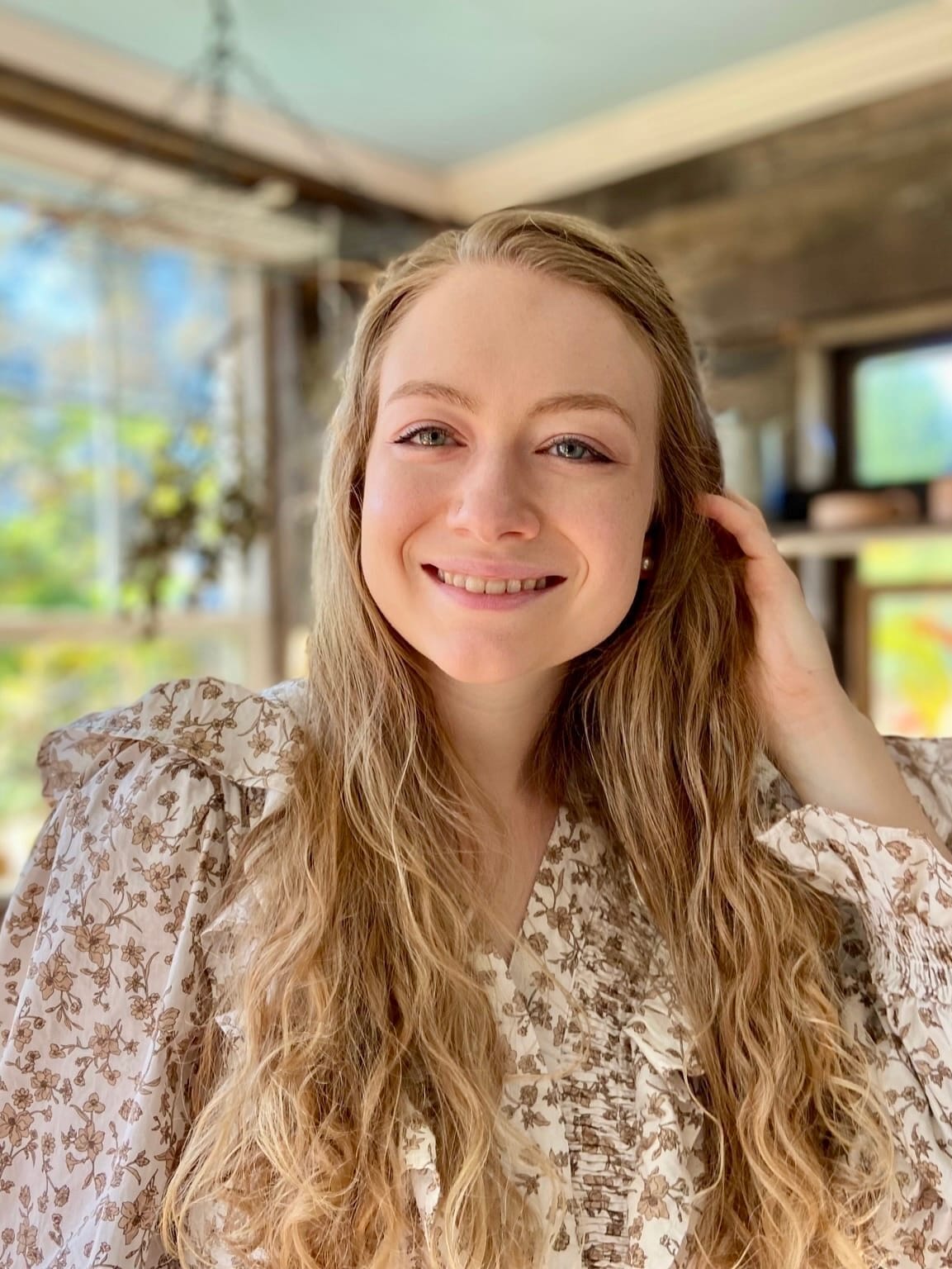 Woman smiling while standing in a sunny room.