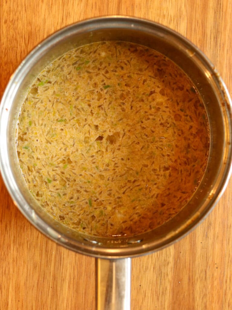 Lime juice, eggs, and other ingredients whisked together in a stainless steel saucepan.