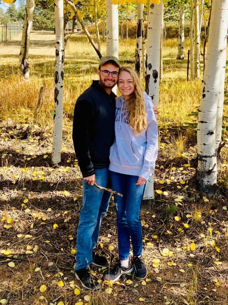 Man and woman standing in front of fall foliage.