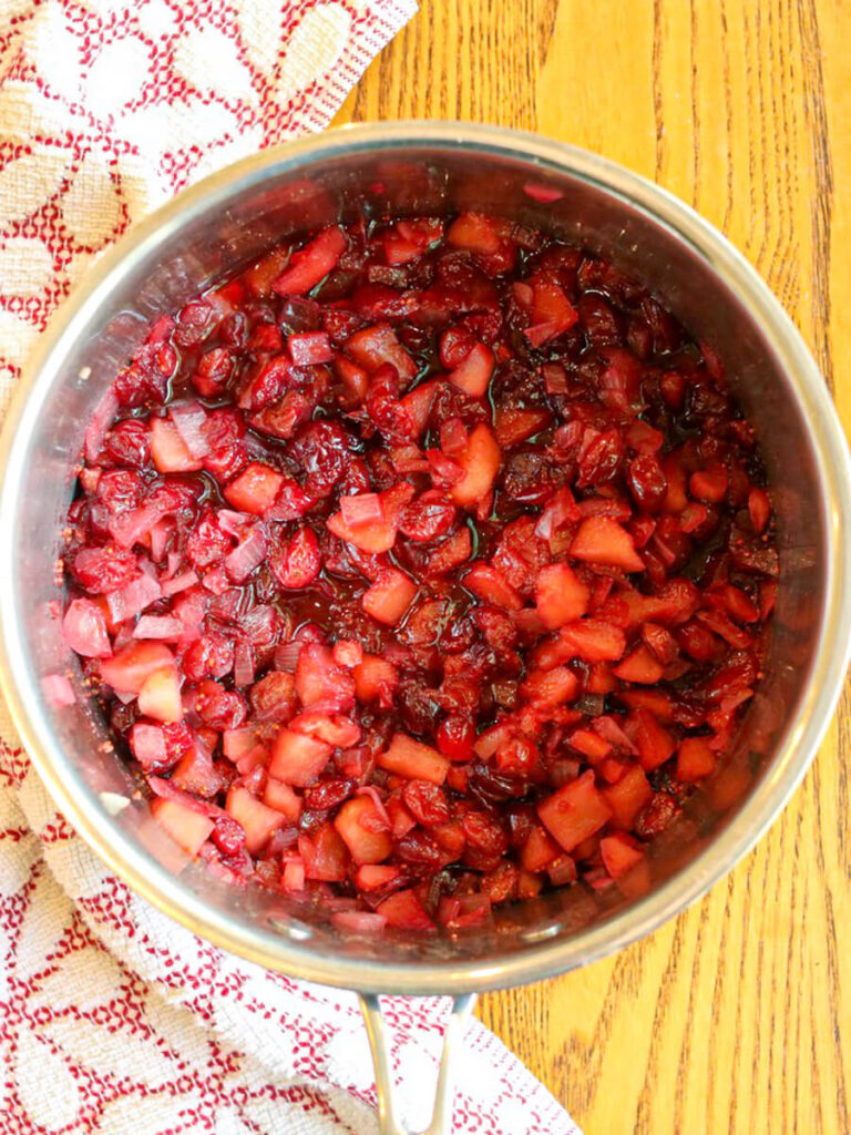 Apple cranberry chutney simmering in a medium saucepan.
