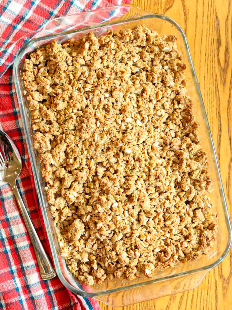 Gluten and dairy-free apple crisp fresh out of the oven resting on a wooden surface.
