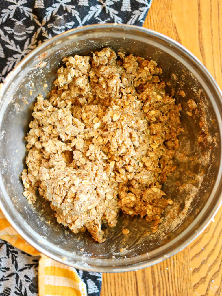 Oat topping mixed in a metal bowl on a wooden surface.
