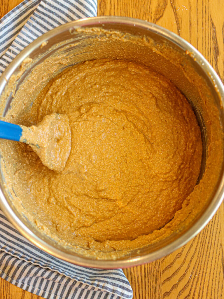 Combining wet and dry batter ingredients in a metal bowl with a silicone spatula.