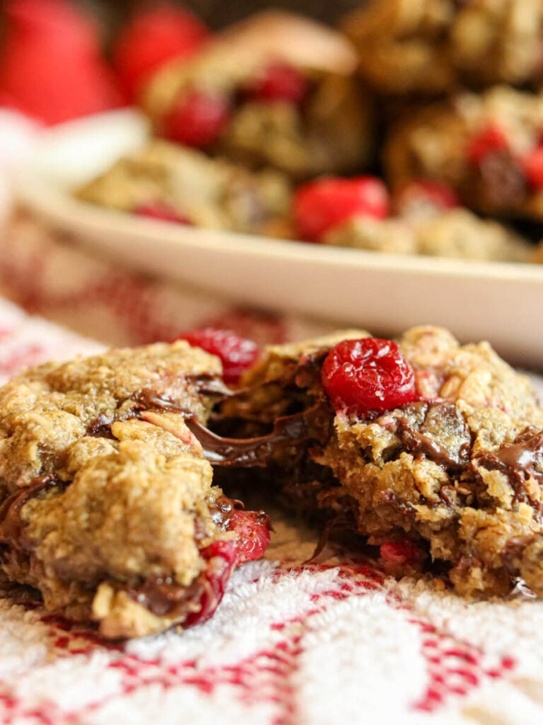 Chocolate cranberry cookie split in half showing a soft texture and gooey melted chocolate.