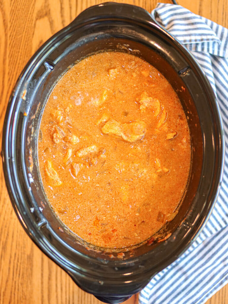 Coconut cream stirred into chicken curry in a slow cooker.