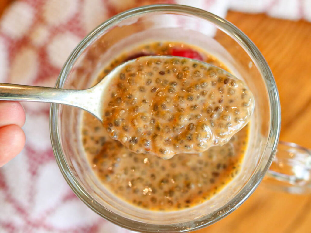 Pumpkin chia seed pudding being scooped with a spoon out of a glass.