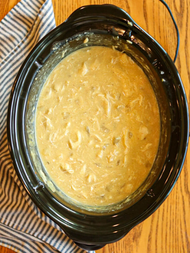Shredded chicken in a yellow honey mustard sauce in a crockpot.