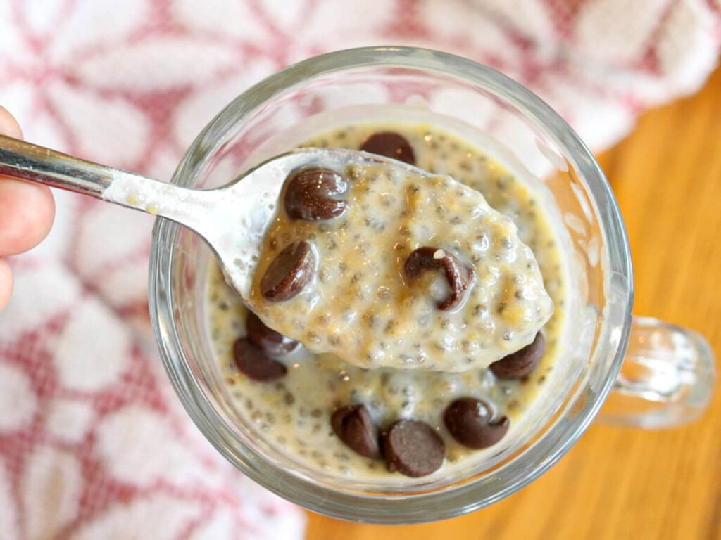 A spoon scooping a bite of high protein chia seed pudding out of a serving glass.