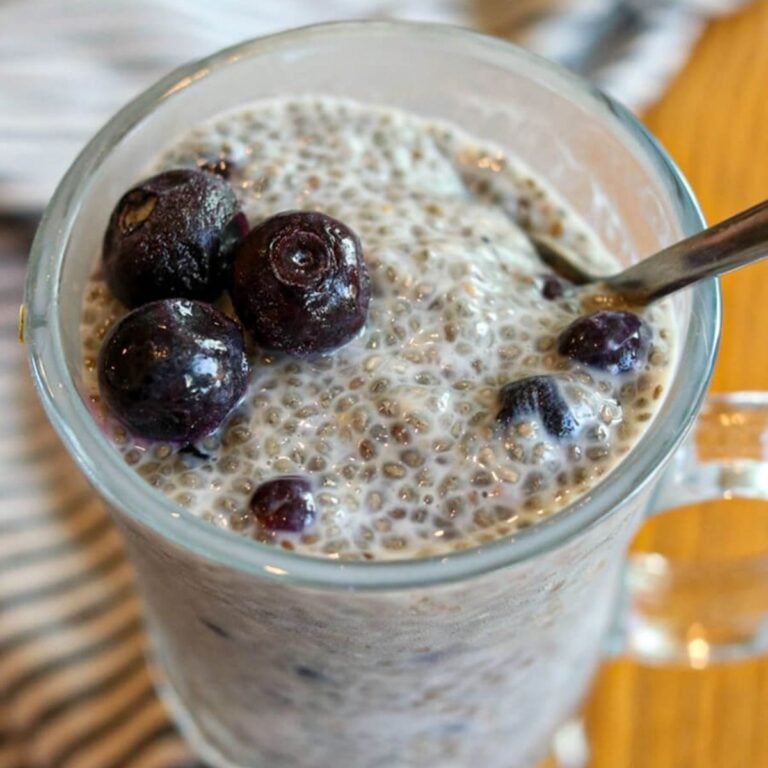 Closeup view of blueberry chia seed pudding in a glass with a spoon in it.