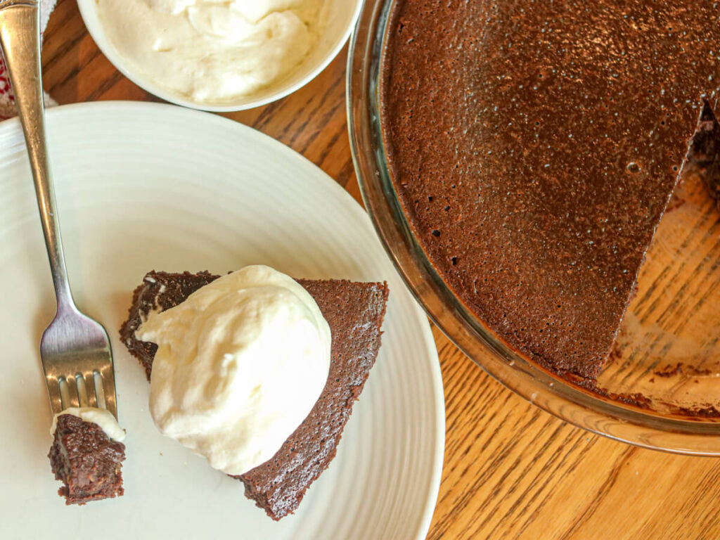 Gluten-free oat flour fudge pie in pie pan and on a plate with whipped cream.