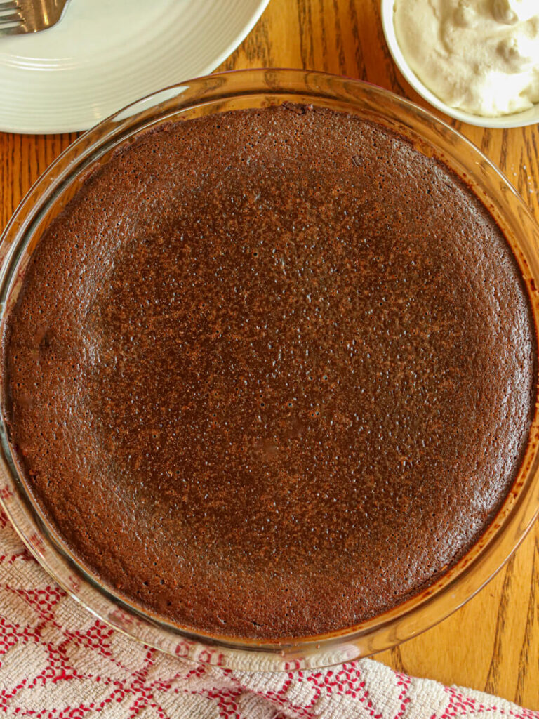 Oat flour fudge pie just out of the oven cooling on a wood table.