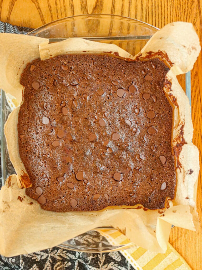 Baked oat flour brownies in a glass pan on a table.