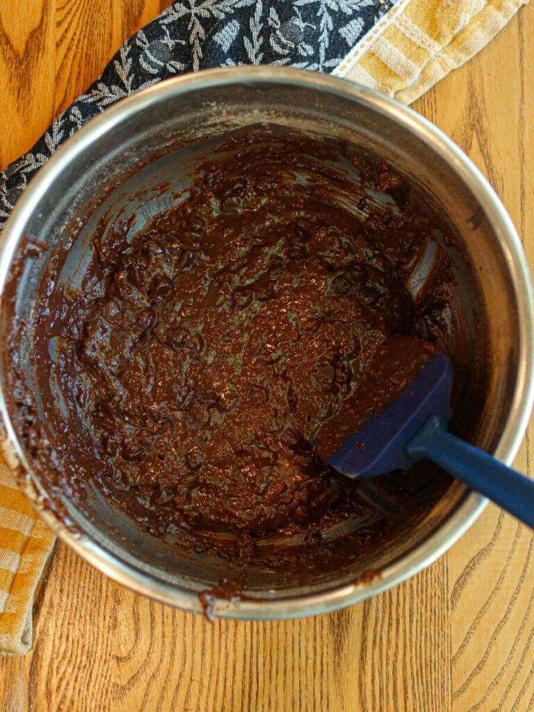 Brownie batter in a mixing bowl on a wood table.
