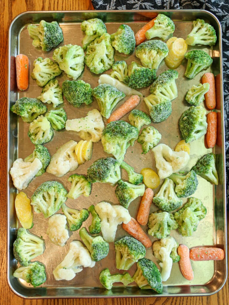 Frozen mixed vegetables spread evenly on a baking sheet.